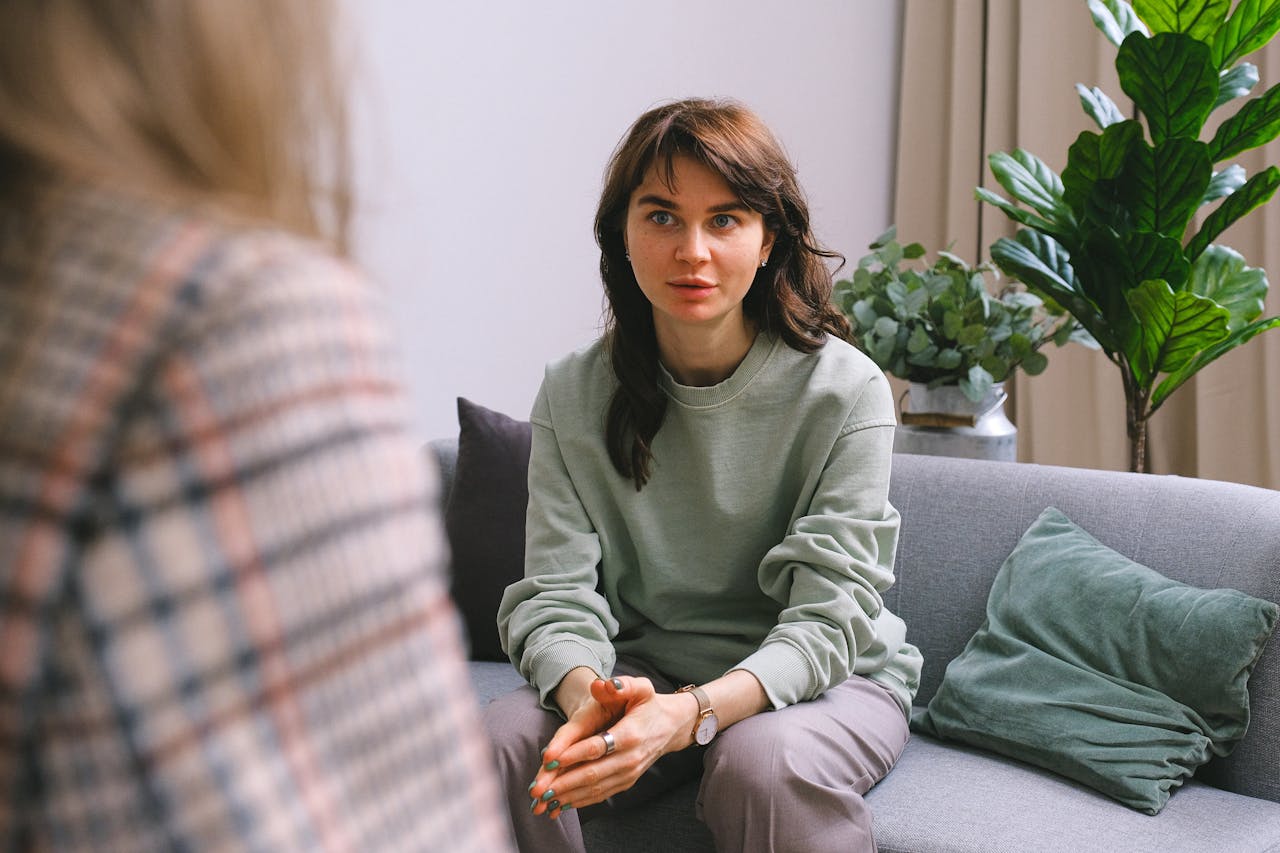 The Art of Drawing Readers In: Your attractive post title goes here A focused woman during a therapy session, seated on a sofa indoors.